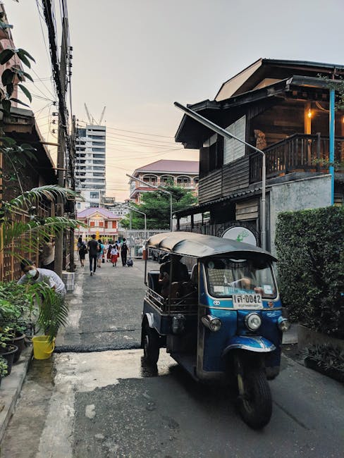 Bangkok street scene featuring a tuk-tuk amidst traditional and modern architecture.